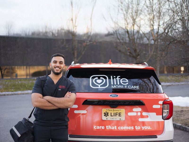 A Life Primary Care clinician with his visit bag beside a marked practice car